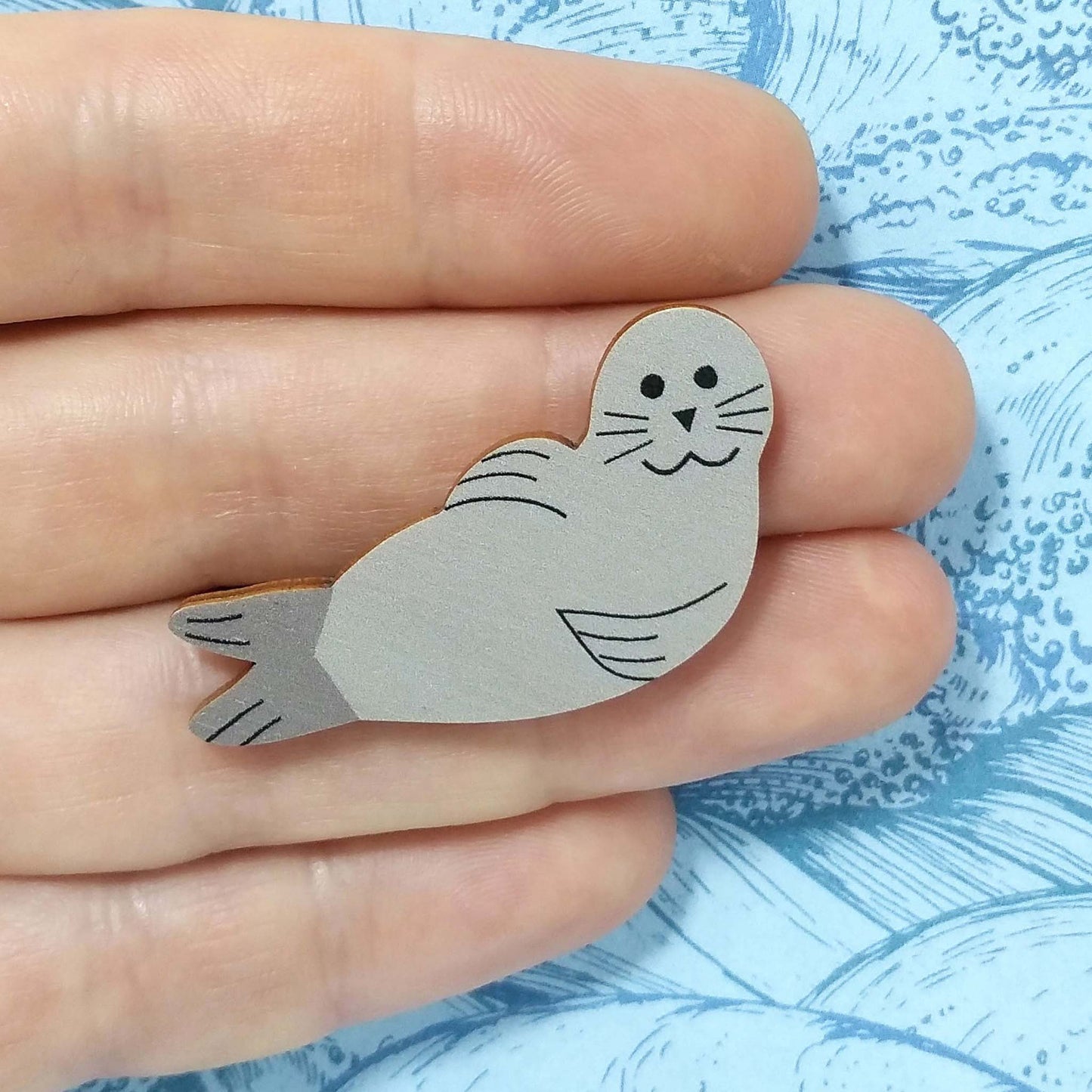 Wooden seal pin badge held on hand