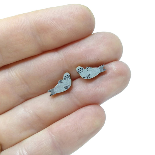 Wooden seal stud earrings held on hand