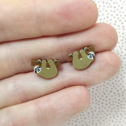 Wooden sloth stud earrings held on hand