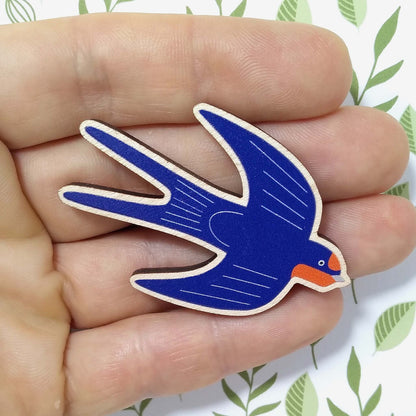 Wooden swallow pin badge held on hand