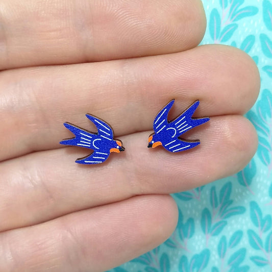 Wooden swallow stud earrings held on hand