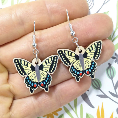 Wooden dangling swallowtail earrings held on hand