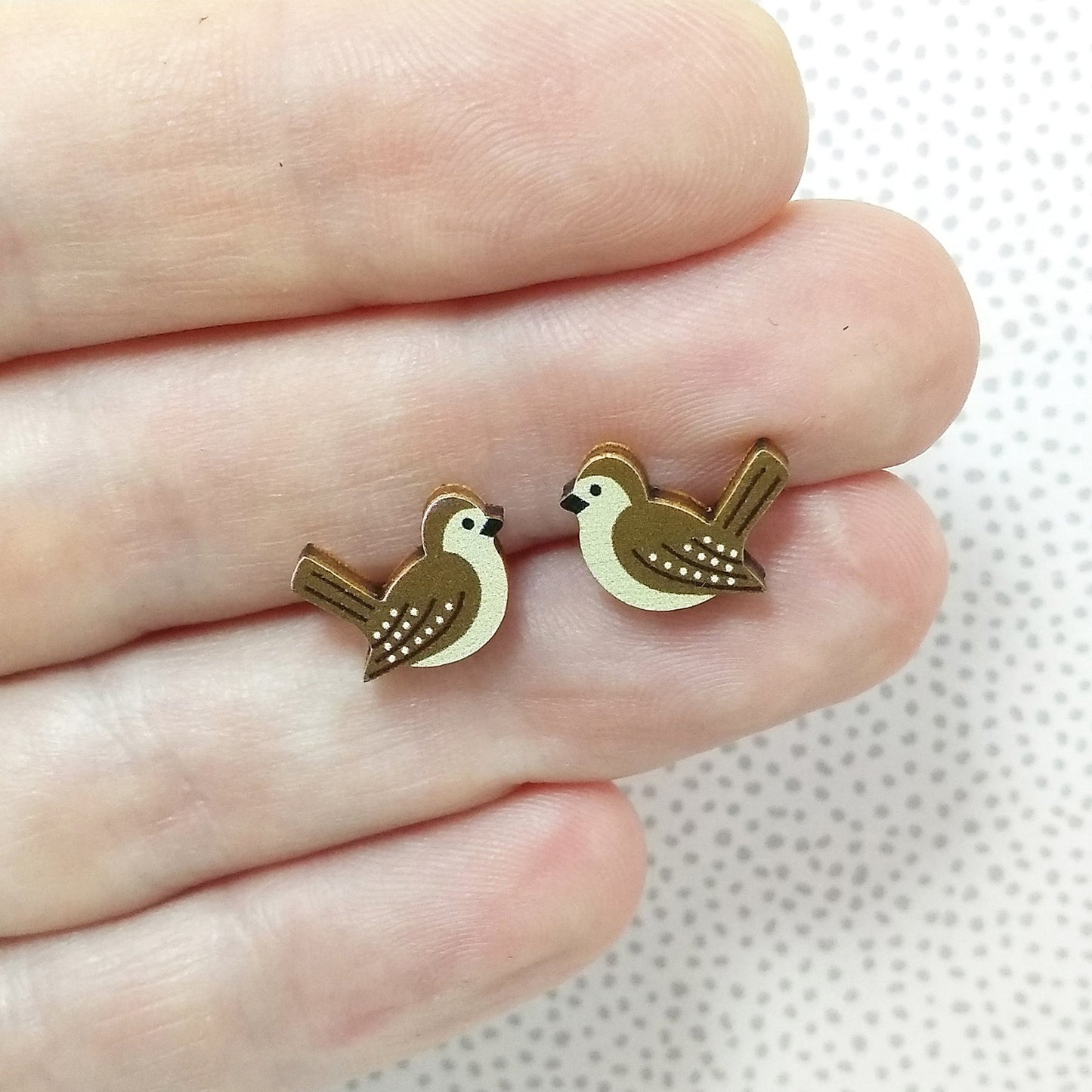 Wooden wren stud earrings held on hand