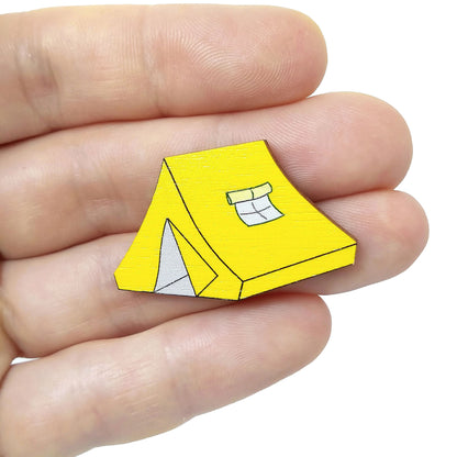 Wooden yellow tent pin badge held on hand