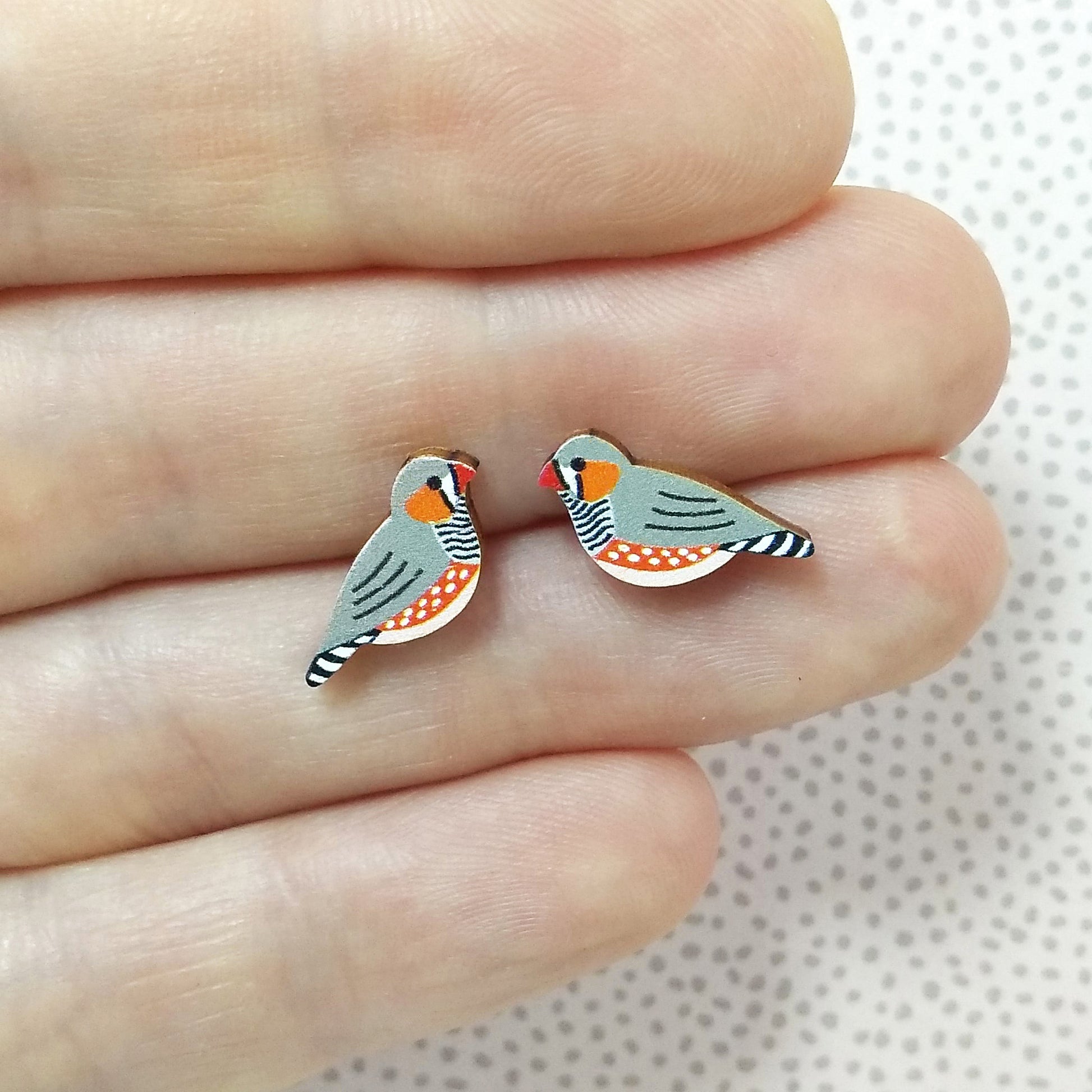 Wooden zebra finch stud earrings held on hand