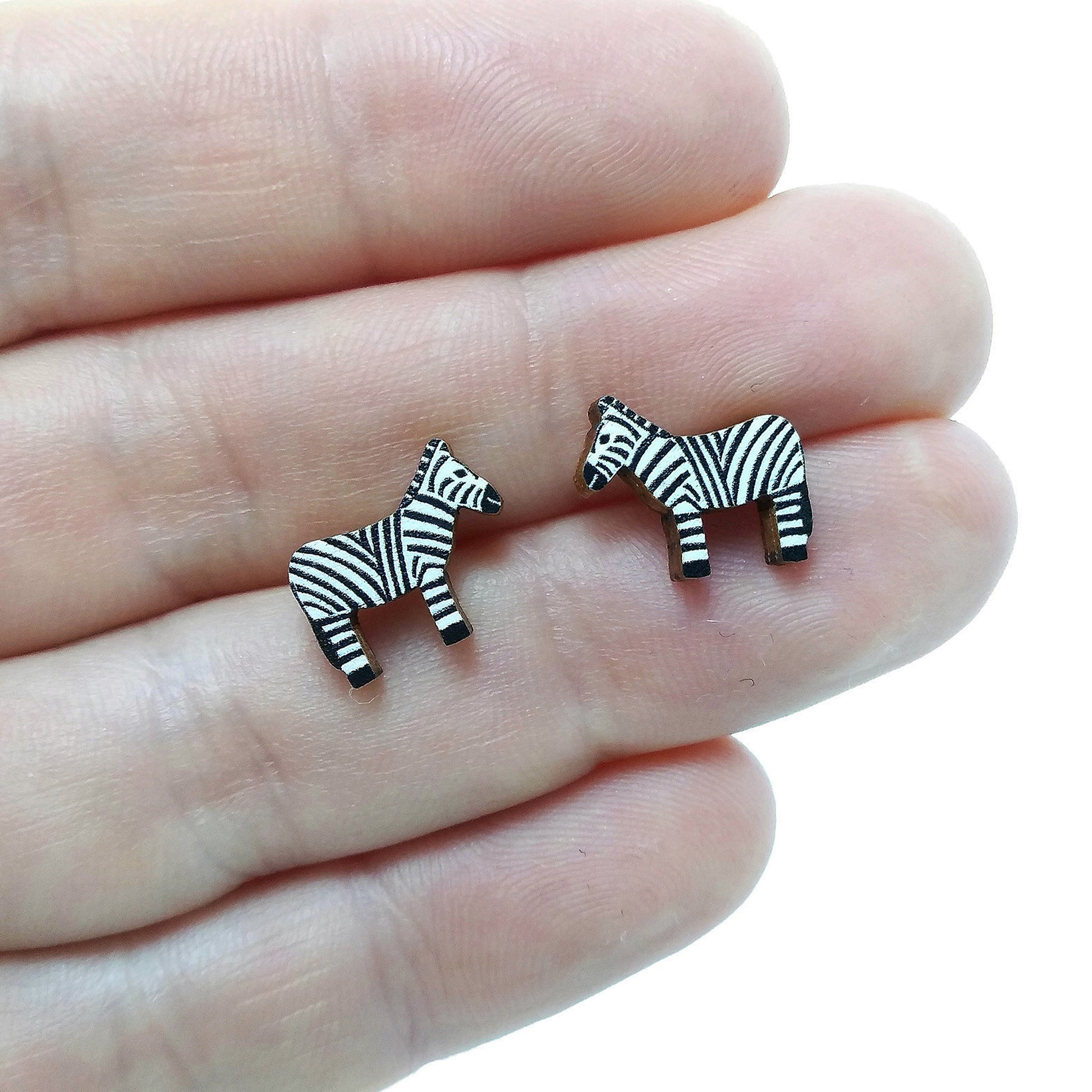 Wooden zebra stud earrings held on hand